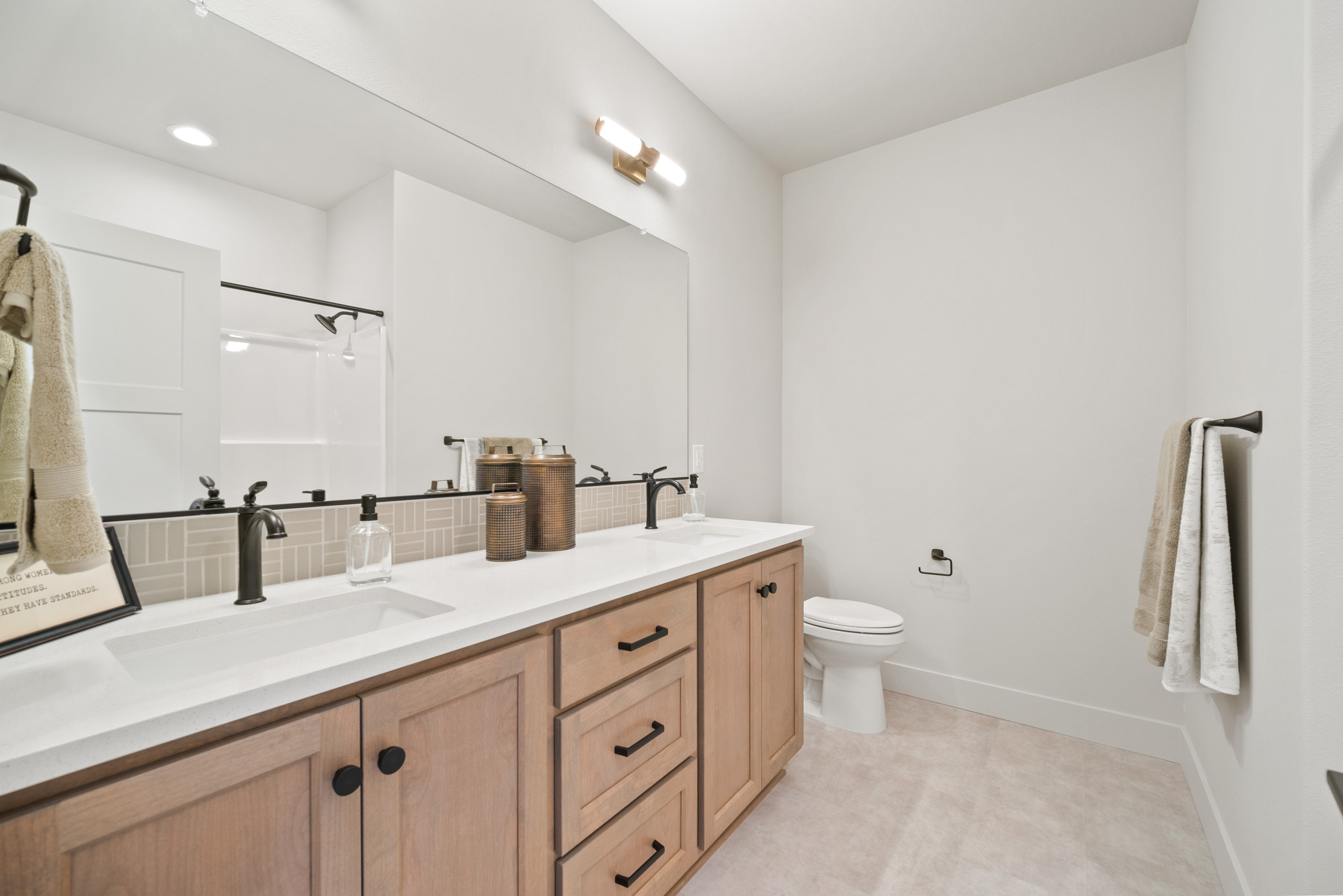 Modern bathroom with wooden vanity and white walls.