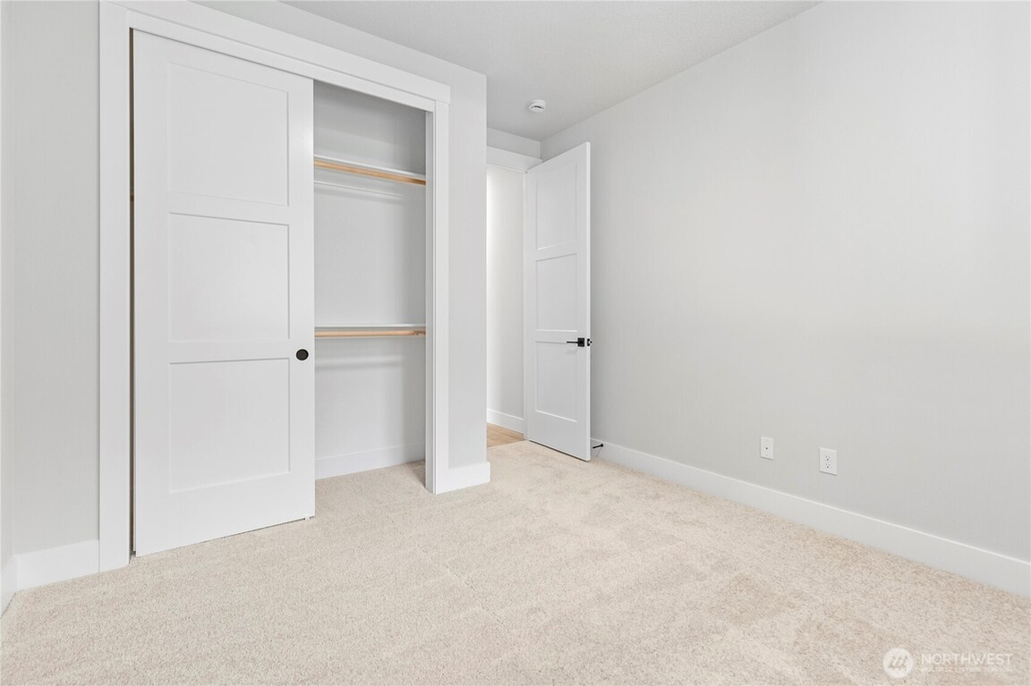 Empty room with beige carpet and open closet doors.