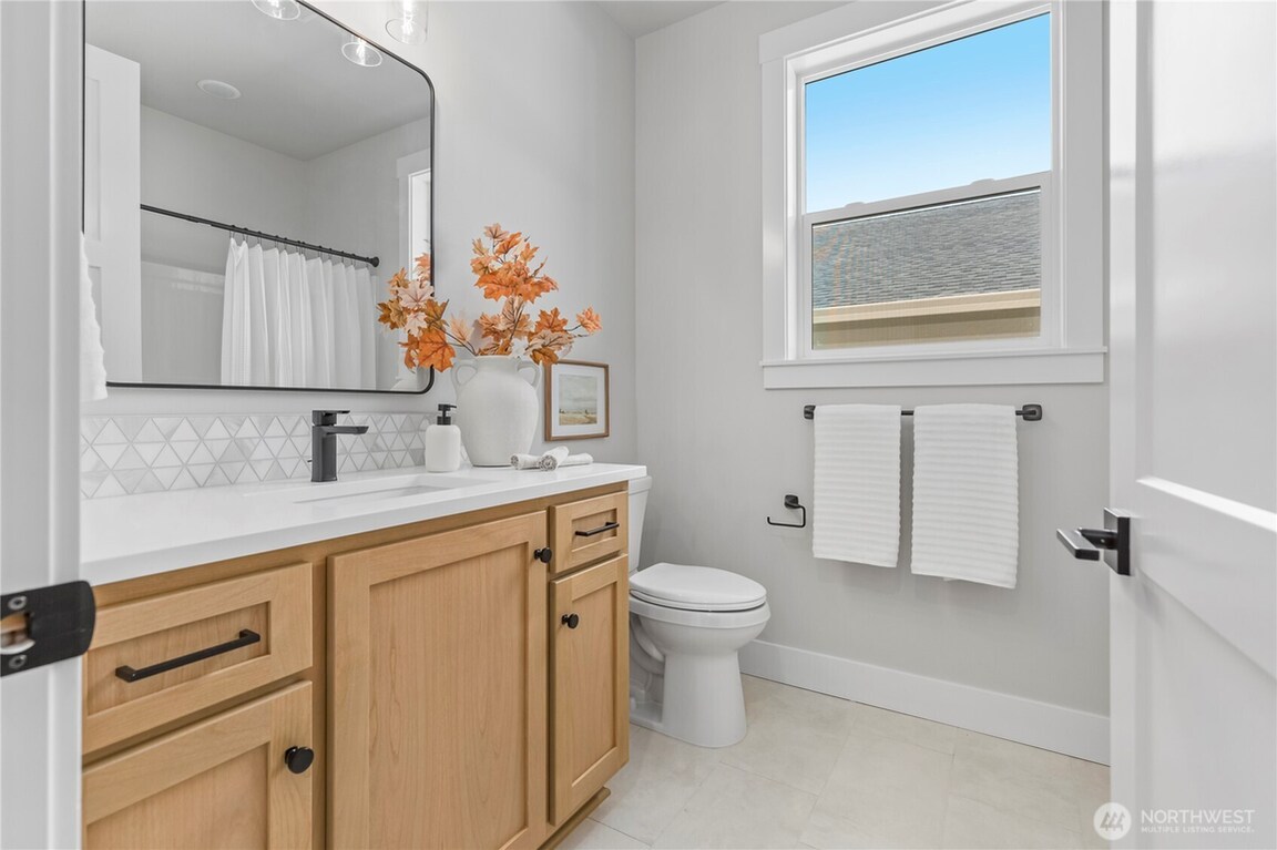 Bright bathroom with wooden vanity and large window.