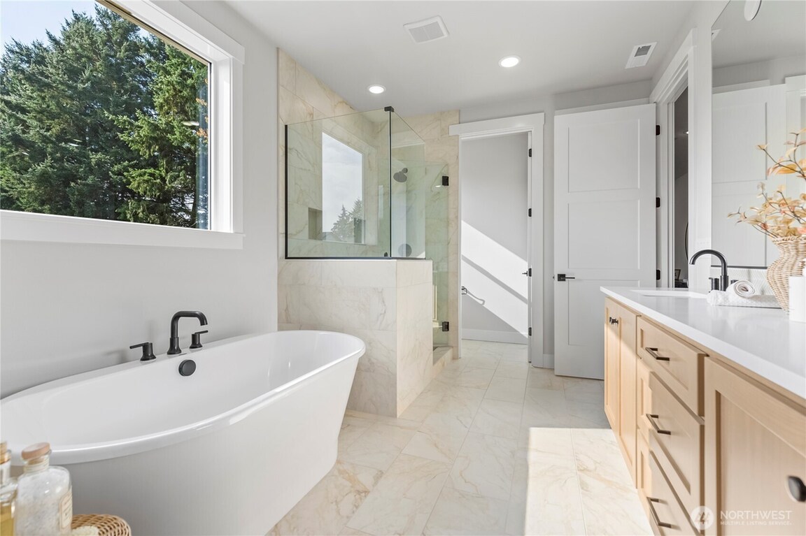 Bright modern bathroom with a bathtub and glass shower enclosure.
