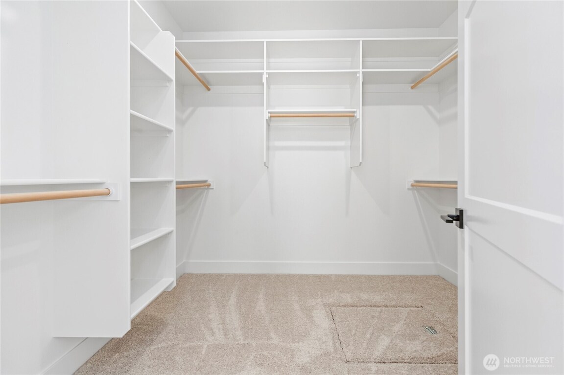 Empty walk-in closet with white shelves and beige floor.