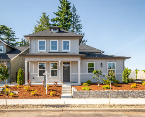 Modern two-story house with a well-maintained front yard and clear blue sky.