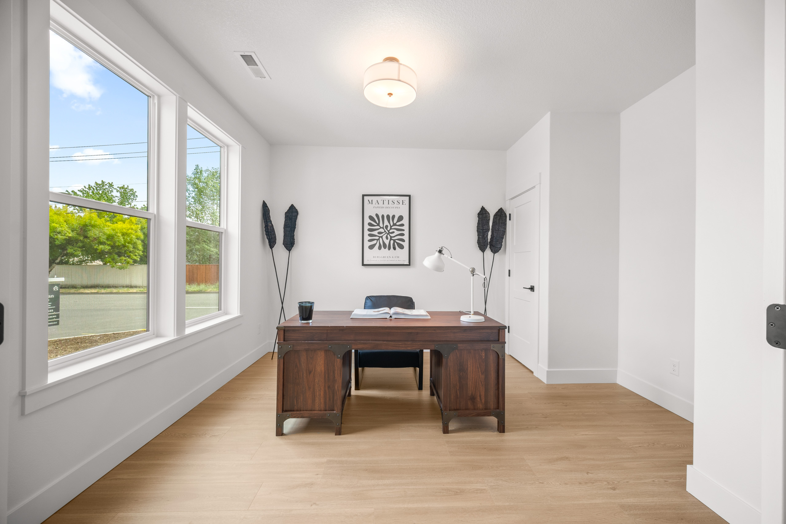 Modern office with wooden desk and large window.