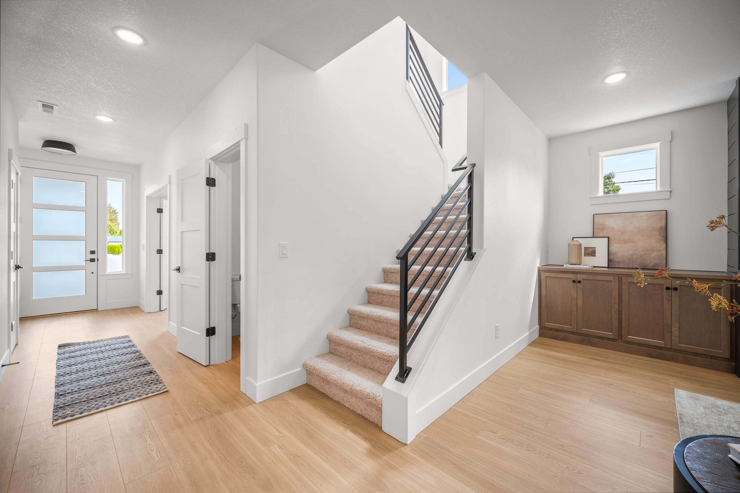 Bright modern hallway with wooden floors and white staircase.