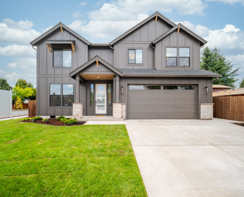 Modern two-story house with a manicured lawn and attached garage.