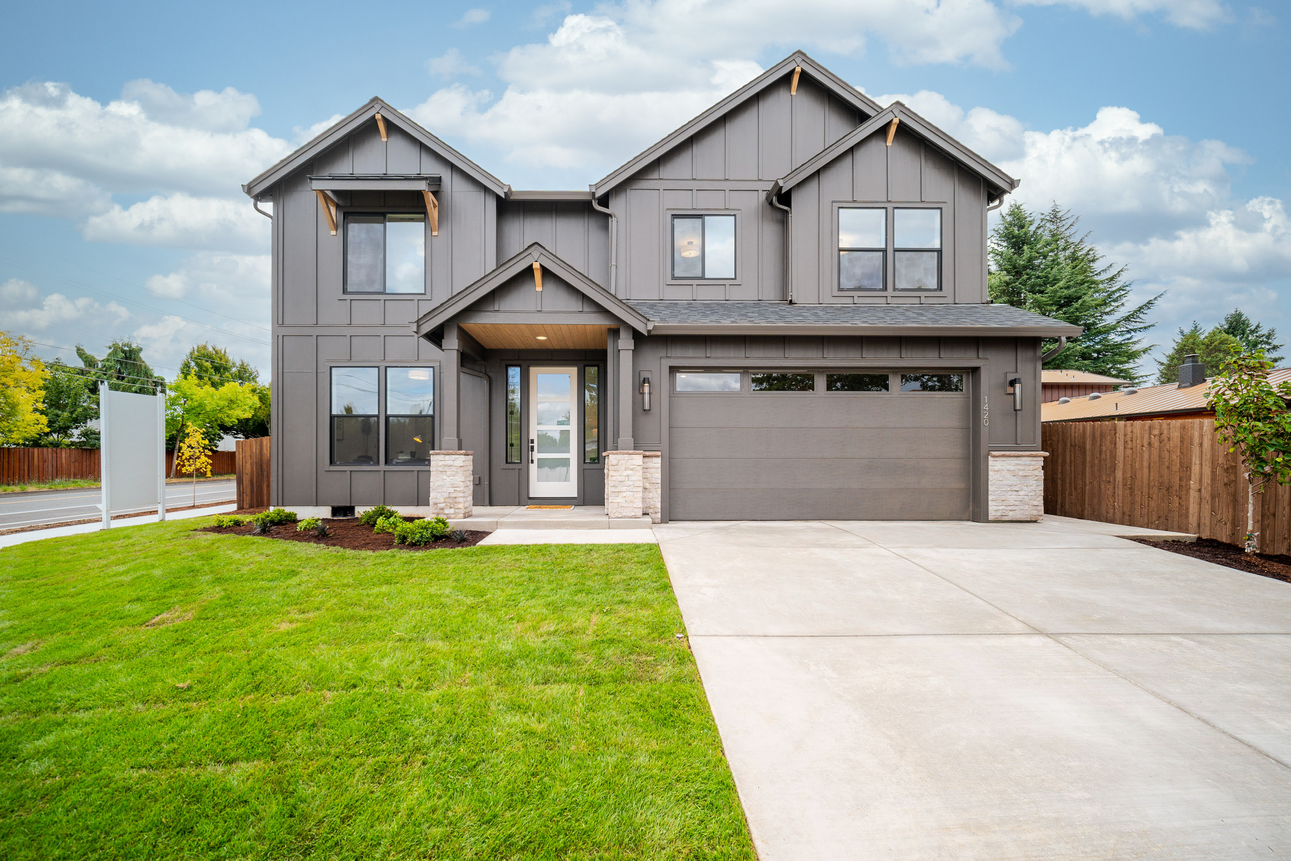 Modern two-story house with a manicured lawn and attached garage.