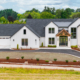 Modern white houses with clean landscaping under a cloudy sky.