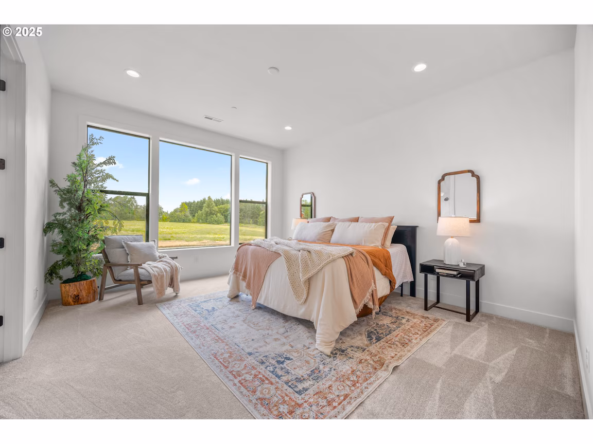 Bright bedroom with large windows overlooking a scenic view.