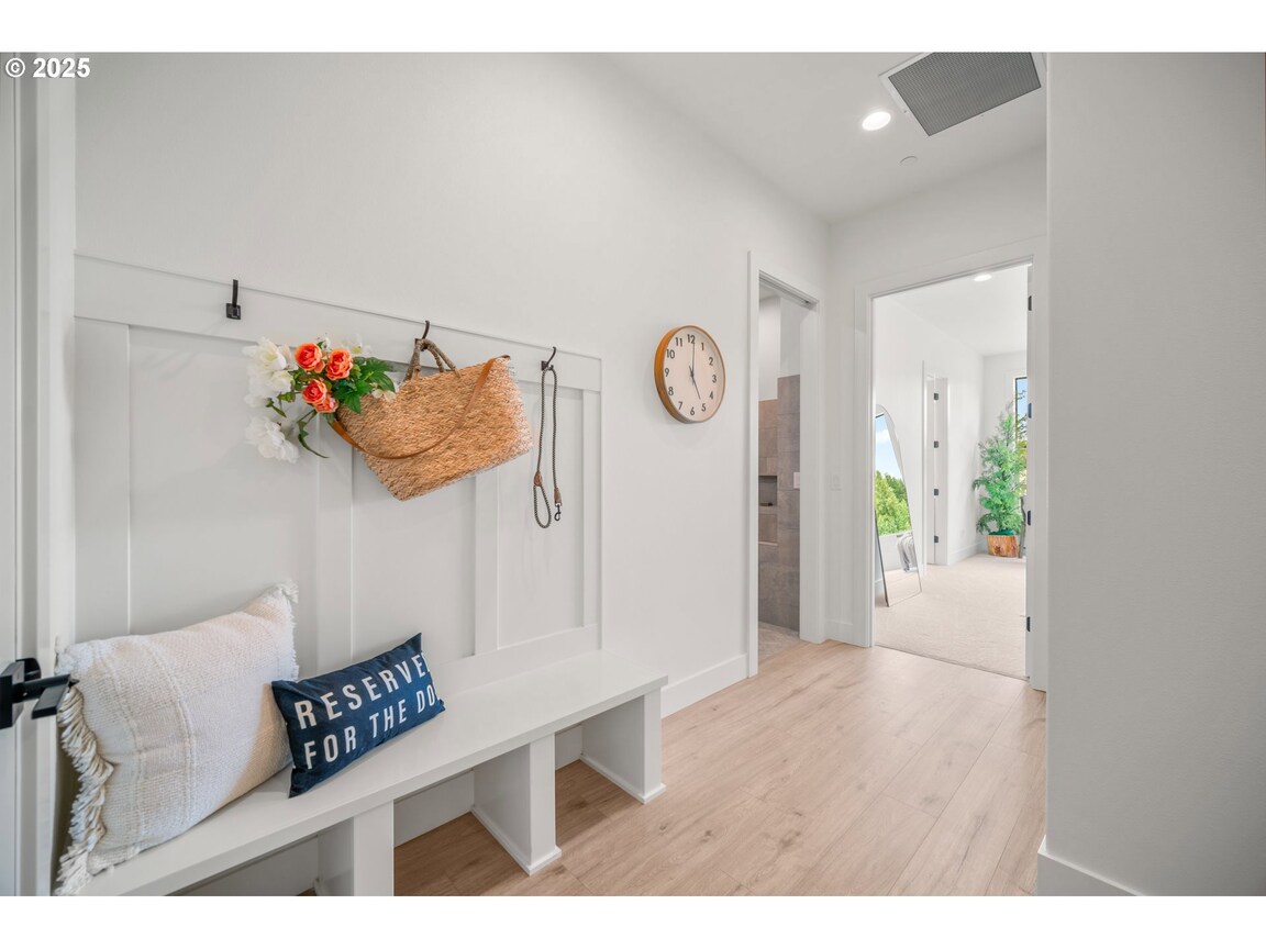 Bright entryway with white walls, a bench, and colorful wall hooks.