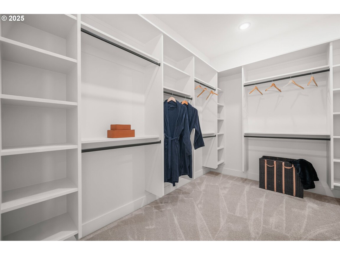 Minimalist walk-in closet with white shelves and a few hanging clothes.