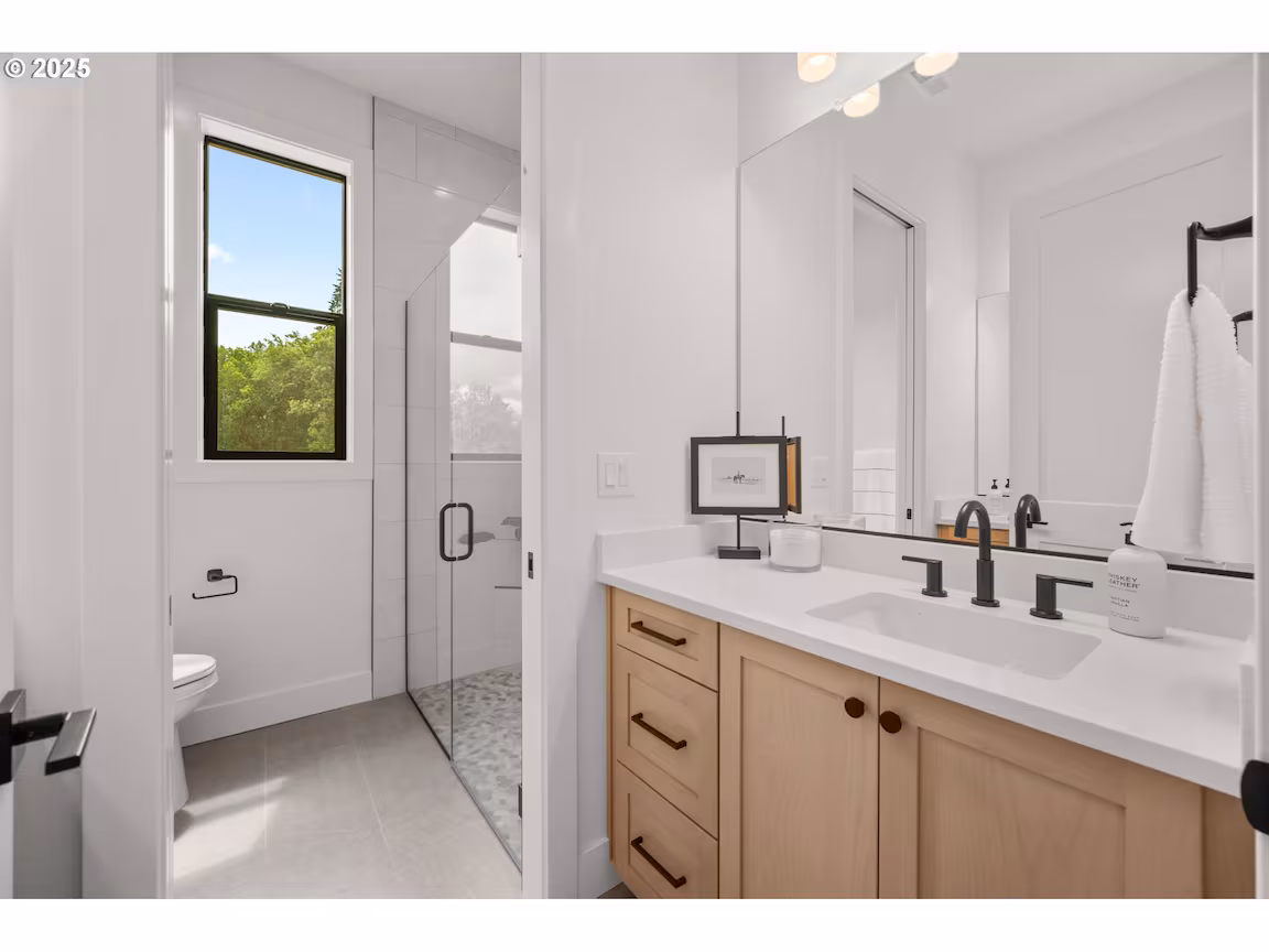 Modern bathroom with glass shower and double sink vanity.