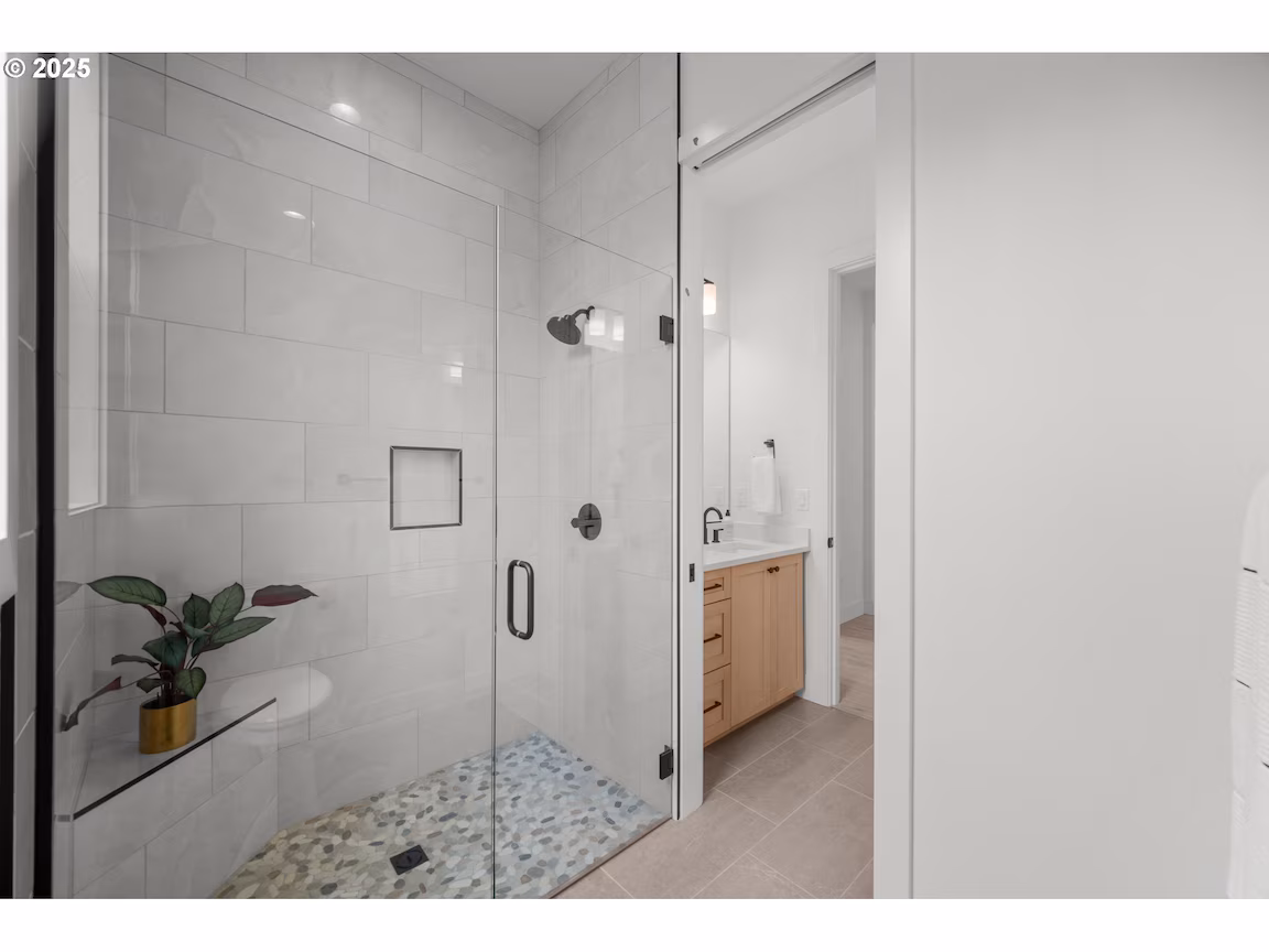 Modern bathroom with white tiles and wooden vanity.