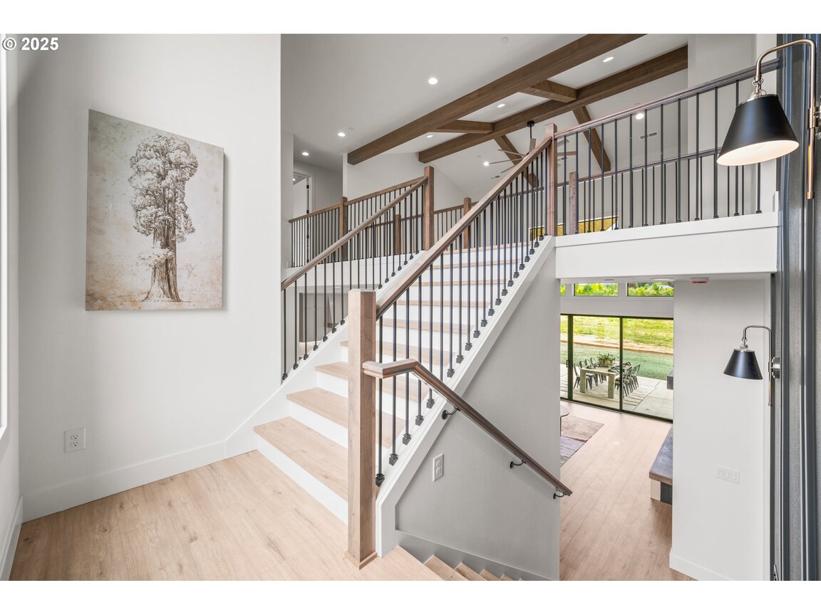 Modern staircase with wood steps and glass railing in a bright home.