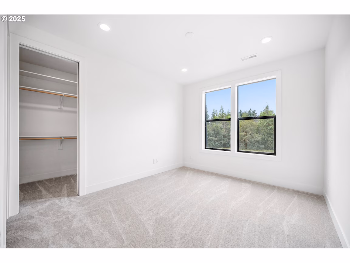 Empty modern room with large window and carpeted floor.