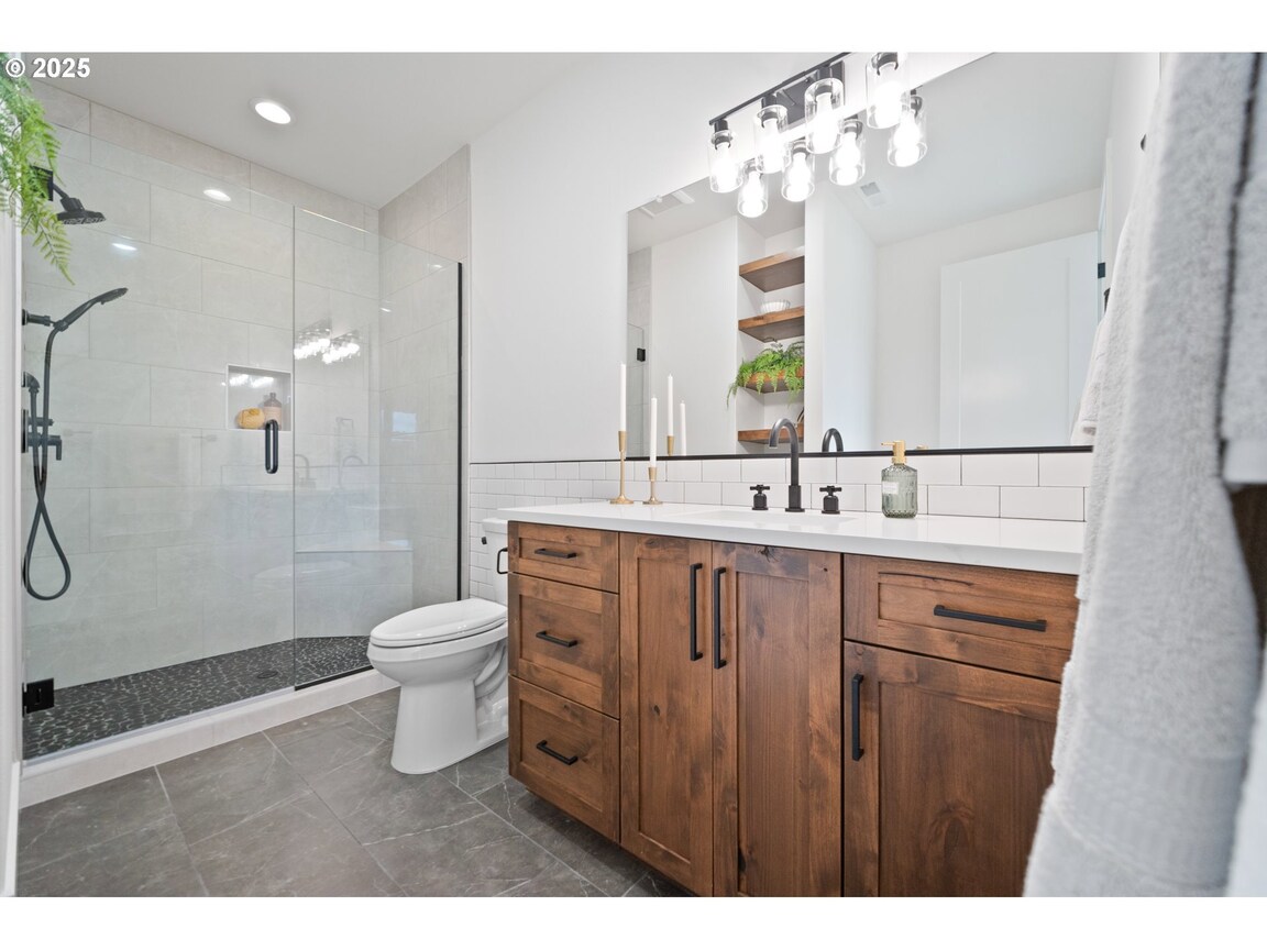 Modern bathroom with wooden vanity and glass shower.