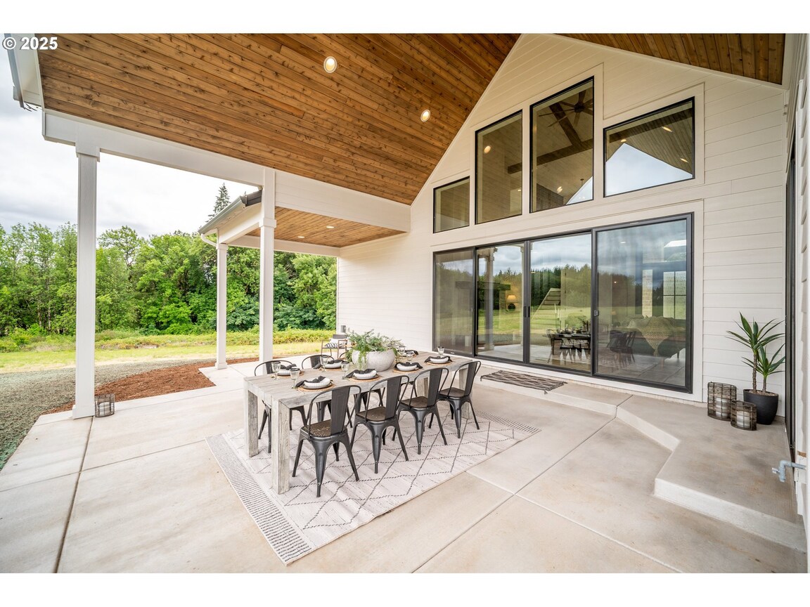 Spacious outdoor patio with modern dining set and wooden ceiling.