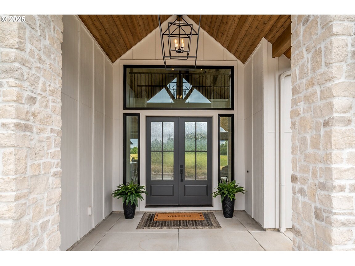 Elegant front porch with black door and wooden ceiling.
