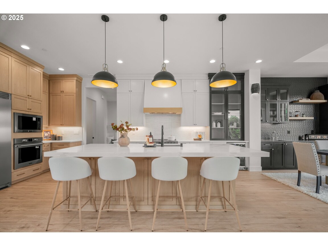 Modern kitchen with island and white bar stools.