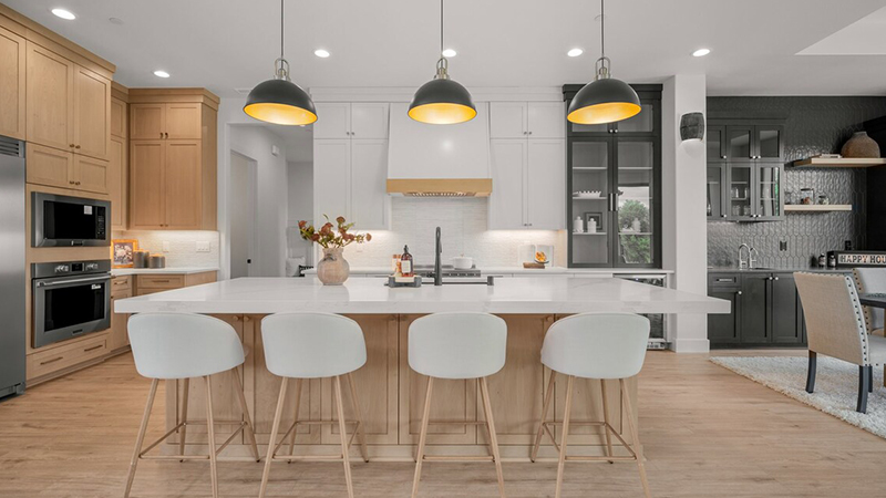 Modern kitchen with white chairs and wooden island under pendant lights. Modern kitchen with white chairs and wooden island under pendant lights.