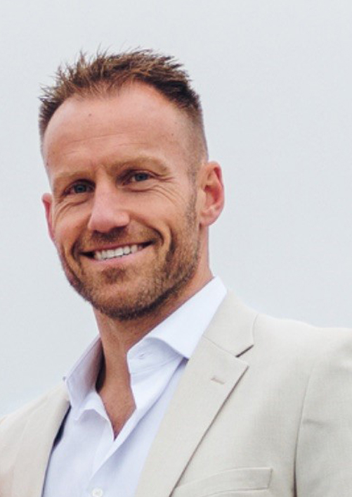 Smiling man in a light beige suit jacket.