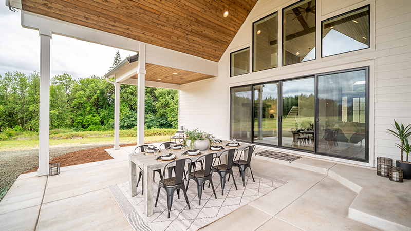 Spacious patio with dining table and modern chairs under wooden ceiling.